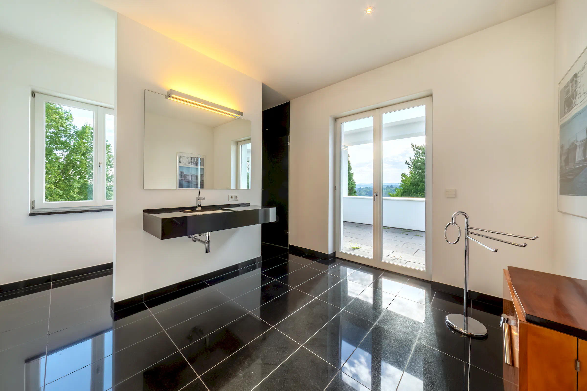 Badezimmer mit schwarzen Steinfliesenböden, Panoramafenstern und Terrassenzugang in der Villa Sonnenberg